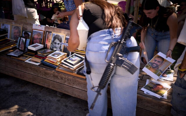 A woman carrying an M-16 rifle helps re-frame photos of victims of the Hamas onslaught of October 7, 2023, as Israelis tend to the makeshift memorial at Tel Aviv's Dizengoff Square on the massacre's second anniversary, October 7, 2025. (AP Photo/Emilio Morenatti) A woman carrying an M-16 rifle helps re-frame photos of victims of the Hamas onslaught of October 7, 2023, as Israelis tend to the makeshift memorial at Tel Aviv's Dizengoff Square on the massacre's second anniversary, October 7, 2025. (AP Photo/Emilio Morenatti)