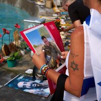 Shiri Tamam, an Israeli-Canadian, holds a photo of an Israeli soldier killed in the Hamas onslaught of October 7, 2023, during a ceremony at Tel Aviv's Dizengoff Square marking two years since the invasion that sparked the Gaza war, October 7, 2025. (AP Photo/Emilio Morenatti)