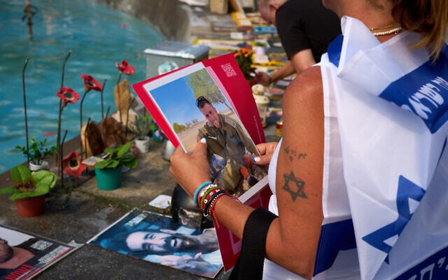 Shiri Tamam, an Israeli-Canadian, holds a photo of an Israeli soldier killed in the Hamas onslaught of October 7, 2023, during a ceremony at Tel Aviv's Dizengoff Square marking two years since the invasion that sparked the Gaza war, October 7, 2025. (AP Photo/Emilio Morenatti)