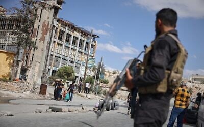 Syrian security forces stand guard as residents leave the Sheikh Maqsoud and Achrafieh neighborhoods of Aleppo, Syria, October 7, 2025, following overnight clashes between Syrian government troops and the Kurdish-led Syrian Democratic Forces. (AP Photo/Omar Albam)