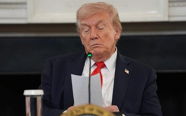 US President Donald Trump reads a note handed to him by Secretary of State Marco Rubio during a roundtable meeting on antifa in the State Dining Room at the White House, October 8, 2025, in Washington. (AP Photo/Evan Vucci)