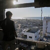A man looks out from his damaged apartment at the destruction in his neighborhood in Gaza City, October 10, 2025, after returning home following an agreement between Israel and Hamas on a ceasefire and the release of remaining hostages. (AP Photo/Jehad Alshrafi)