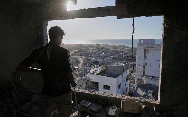 A man looks out from his damaged apartment at the destruction in his neighborhood in Gaza City, October 10, 2025, after returning home following an agreement between Israel and Hamas on a ceasefire and the release of remaining hostages. (AP Photo/Jehad Alshrafi)
