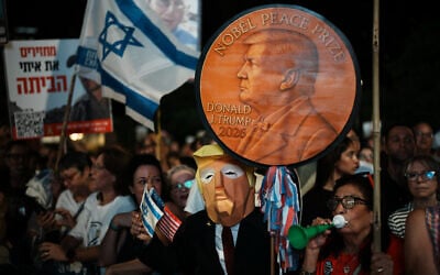 A man wearing a mask resembling US President Donald Trump holds a sign designed like a Nobel Peace Prize medal during a rally in support of hostages held by Hamas, at Hostages Square in Tel Aviv, Israel, October 11, 2025. (AP Photo/Emilio Morenatti)