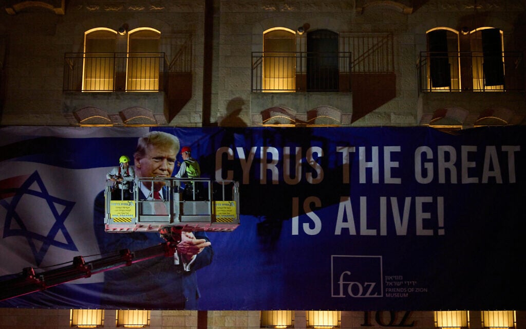 Workers hang a large billboard featuring a picture of US President Donald Trump in Jerusalem, October 12, 2025. (AP Photo/Ohad Zwigenberg)