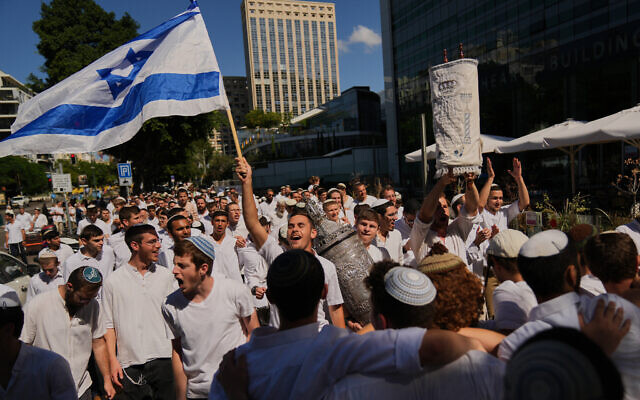 Jewish revelers dance and hold up a Torah scroll as they celebrate the holiday of Simchat Torah, in Tel Aviv, Oct. 14, 2025. (AP Photo/Francisco Seco)