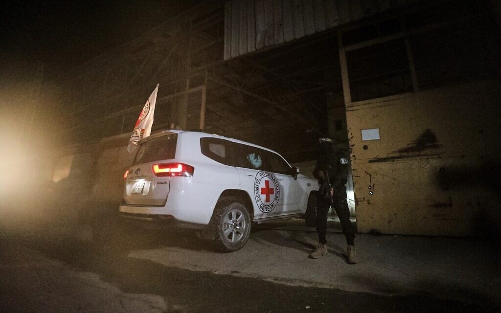 A gunman wearing the uniform of the al-Qassam Brigades, the military wing of Hamas, stands guard as Red Cross vehicles enter a warehouse allegedly to collect coffins containing the bodies of four deceased hostages, in Gaza City, October 14, 2025. (AP Photo/Yousef Al Zanoun)