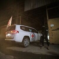 A gunman wearing the uniform of the al-Qassam Brigades, the military wing of Hamas, stands guard as Red Cross vehicles enter a warehouse allegedly to collect coffins containing the bodies of four deceased hostages, in Gaza City, October 14, 2025. (AP Photo/Yousef Al Zanoun)