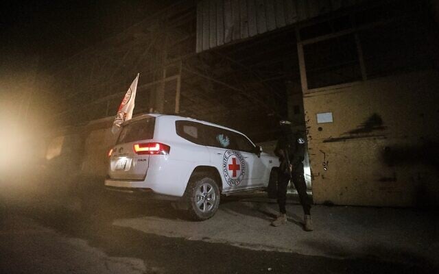 A gunman wearing the uniform of the al-Qassam Brigades, the military wing of Hamas, stands guard as Red Cross vehicles enter a warehouse allegedly to collect coffins containing the bodies of four deceased hostages, in Gaza City, October 14, 2025. (AP Photo/Yousef Al Zanoun)