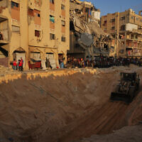 Palestinians watch members of the Hamas militant group searching for bodies of the hostages in an area in Hamad City, Khan Younis, in the southern Gaza Strip, Friday, Oct. 17, 2025. (AP Photo/Abdel Kareem Hana)