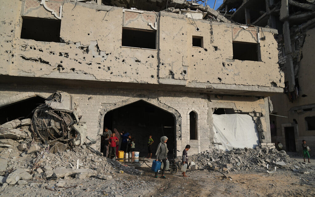 Displaced Palestinians collect water from a destroyed building in Khan Younis, Gaza Strip, October 18, 2025. (AP Photo/Jehad Alshrafi)