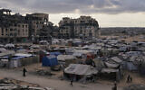 A tent camp for displaced Palestinians sits adjacent to destroyed homes and buildings in Khan Younis, Gaza Strip, October 18, 2025. (AP Photo/Jehad Alshrafi)