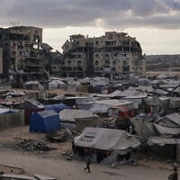 A tent camp for displaced Palestinians sits adjacent to destroyed homes and buildings in Khan Younis, Gaza Strip, October 18, 2025. (AP Photo/Jehad Alshrafi)
