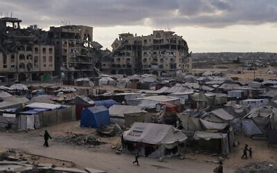 A tent camp for displaced Palestinians sits adjacent to destroyed homes and buildings in Khan Younis, Gaza Strip, October 18, 2025. (AP Photo/Jehad Alshrafi)