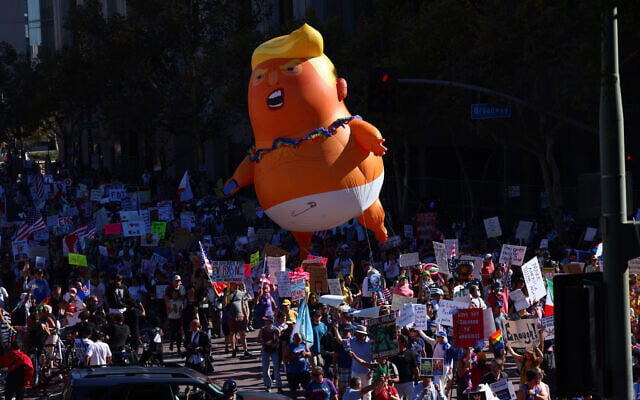 Pulling a giant inflatable Donald Trump protesters march in the streets during a 'No Kings' protest in Los Angeles, October 18, 2025. (Ethan Swope/AP)