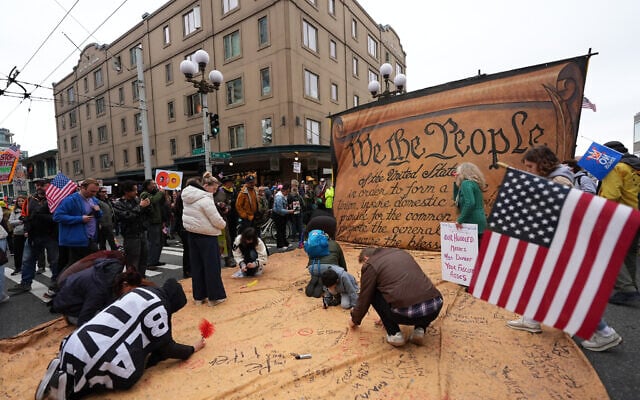 People sign a giant Constitution as they take part in a 'No Kings' protest in Seattle, October 18, 2025. (Lindsey Wasson/AP)
