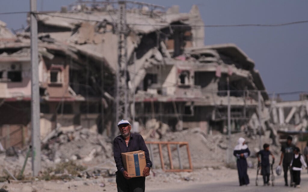 A Palestinian man carries a box of food from the World Food Programme (WFP) after collecting it in Khan Younis, in the southern Gaza Strip, on October 20, 2025. (AP Photo/Jehad Alshrafi)