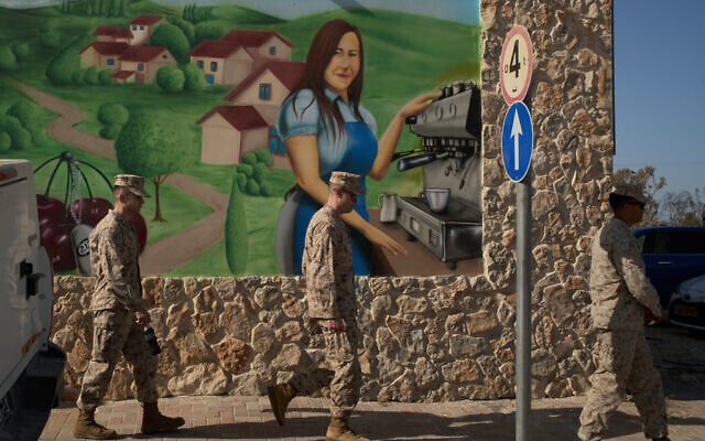 US Marine soldiers walk past a mural of a coffee shop near Kibbutz Kfar Aza, southern Israel, Tuesday, Oct. 21, 2025. (AP Photo/Leo Correa)