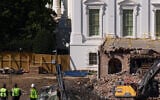 Construction workers atop the US Treasury, bottom left, watch as work continues on a largely demolished part of the East Wing of the White House, October 23, 2025, in Washington, before construction of a new ballroom. (AP Photo/Jacquelyn Martin)