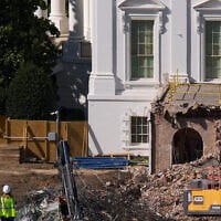 Construction workers atop the US Treasury, bottom left, watch as work continues on a largely demolished part of the East Wing of the White House, October 23, 2025, in Washington, before construction of a new ballroom. (AP Photo/Jacquelyn Martin)
