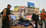 A vendor selling clothes in front of an Iraqi parliamentary elections banner in Baghdad, Iraq, October 16, 2025. (AP/Hadi Mizban)