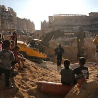 Palestinians watch machinery and some workers from Egypt searching for the bodies of hostages at Hamad City, in Khan Younis, southern Gaza Strip, October 26, 2025. (AP/Jehad Alshrafi)