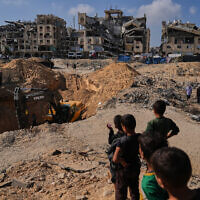 Palestinians watch as Egyptian machinery and workers search for the bodies of hostages in Hamad City, Khan Younis, in the southern Gaza Strip, Oct. 28, 2025. (AP Photo/Abdel Kareem Hana)