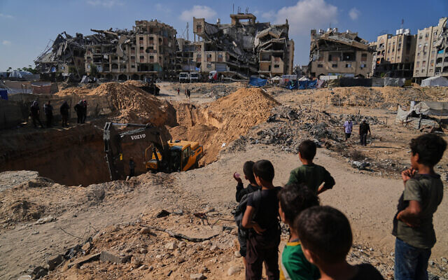 Palestinians watch as Egyptian machinery and workers search for the bodies of hostages in Hamad City, Khan Younis, in the southern Gaza Strip, Oct. 28, 2025. (AP Photo/Abdel Kareem Hana)