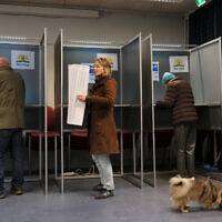 A woman holds a sheet of candidates as she prepares to vote at a polling station during general elections in The Hague, Netherlands, October 29, 2025. (AP Photo/Patrick Post)