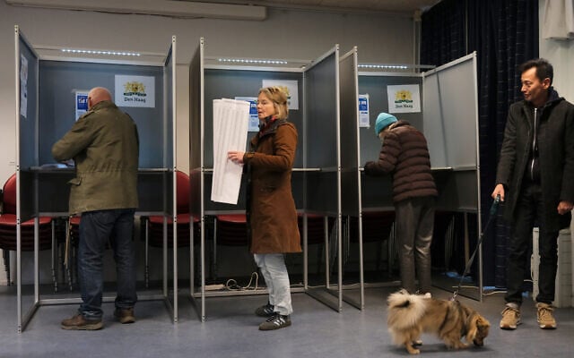 A woman holds a sheet of candidates as she prepares to vote at a polling station during general elections in The Hague, Netherlands, October 29, 2025. (AP Photo/Patrick Post)