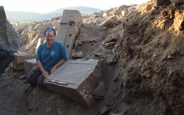Abbie Rosenbaum Braha, area supervisor at the archaeological excavation in the Yehudiya Nature Reserve in the Golan, stands next to an ancient ‘tabula ansata,’ (large stone table with dovetail handles) found in an approximately 1,500-year-old synagogue whose discovery was announced on October 5, 2025. (Dr. Mechael Osband - University of Haifa/Kinneret Academic College)