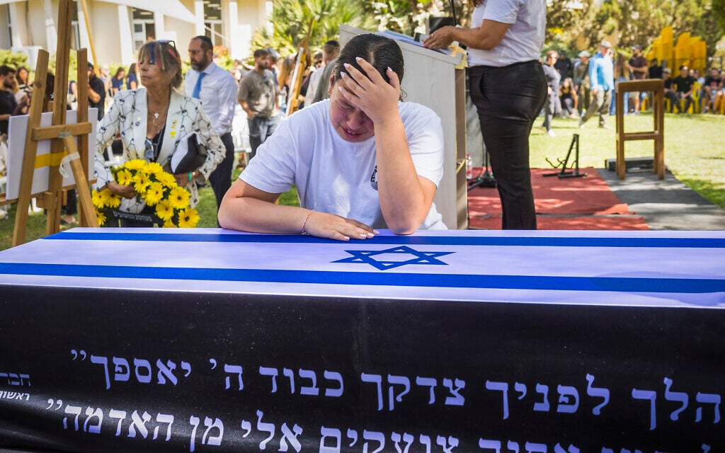 Yuval Engel weeps over the casket of her father, slain hostage Ronen Engel, during his funeral ceremony at Kibbutz Nir Oz on October 21, 2025 (Liron Moldovan/Flash90)