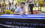 Yuval Engel weeps over the casket of her father, slain hostage Ronen Engel, during his funeral ceremony at Kibbutz Nir Oz on October 21, 2025 (Liron Moldovan/Flash90)