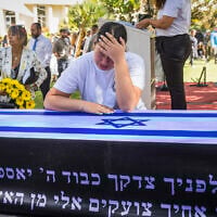 Yuval Engel weeps over the casket of her father, slain hostage Ronen Engel, during his funeral ceremony at Kibbutz Nir Oz on October 21, 2025 (Liron Moldovan/Flash90)