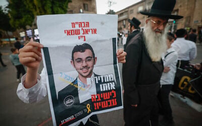 A demonstrator holds up a poster of Haredi draft evader Ariel Shamai which reads: "Bring him back to yeshiva now!" and in smaller print on the left: "Until the last hostage," imitating the rhetoric of the hostage families' protest movement, during an anti-draft demonstration in Jerusalem on October 22, 2025. (Yonatan Sindel/Flash90)