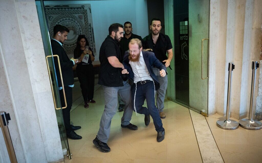 Guards remove ultra-Orthodox Jewish protesters from the courtroom during a hearing on the military draft of ultra-Orthodox Jews, at the Supreme Court in Jerusalem, October 29, 2025 (Chaim Goldberg/Flash90)