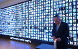 Prime Minister Benjamin Netanyahu lights a candle in memory of the victims of the war against Hamas in Gaza, next to a wall with faces of victims, at the National Library of Israel in Jerusalem, October 12, 2025. (Amos Ben Gershom/GPO)