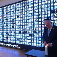Prime Minister Benjamin Netanyahu lights a candle in memory of the victims of the war against Hamas in Gaza, next to a wall with faces of victims, at the National Library of Israel in Jerusalem, October 12, 2025. (Amos Ben Gershom/GPO)