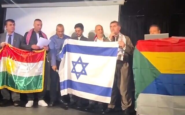 Attendees at the "Future of Minorities in the Middle East" conference in Tel Aviv hold the Kurdish, Israeli and Druze flags as they speak, on October 27, 2025. (Screenshot: X, used in accordance with Clause 27a of the Copyright Law)