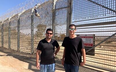 Kibbutz El-Rom emergency response team members Shimon Michael, right, and Gal Fitusi stand at the border fence near the Syrian village of al-Hamidiya on October 23, 2025. (Diana Bletter/Times of Israel)