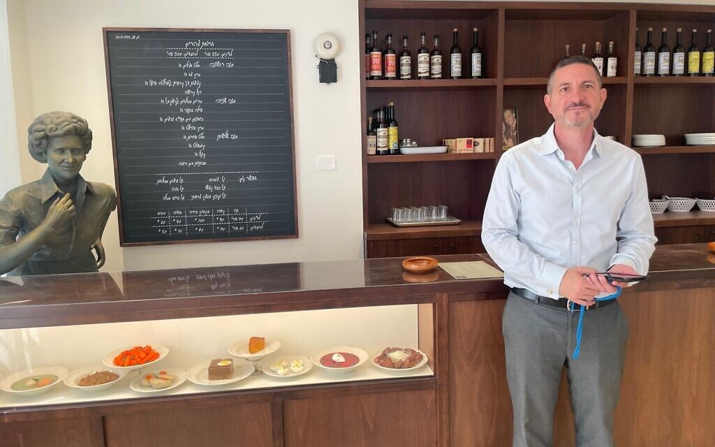 Knesset Museum director Moshe Fuksman-Sha'al at the original cafeteria bar from the original Knesset, now ensconced in the new Knesset Museum, open since August 2025 (Courtesy)