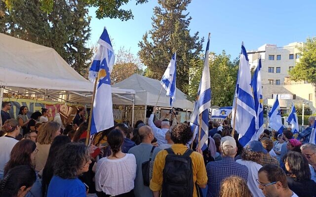A crowd gathers at the hostage families' protest tent on Balfour Street in Jerusalem to watch the release of hostages from Gaza, October 13, 2025. (Zev Stub/Times of Israel)