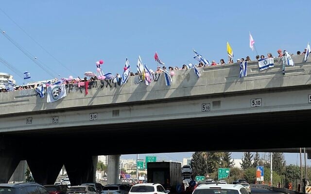 Crowds line the Aluf Sade bridge over Highway 4 in the direction of Petah Tikvah, awaiting the funeral procession of Inbar Haiman, wearing pink in honor of her nickname, Pink, on October 1, 2025. (Yael Gadot/Israeli Pro-Democracy Protest Movement)