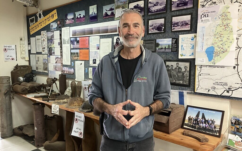 Erez Boshy of Kibbutz El-Rom in the Golan Heights, stands in the kibbutz visitor center in front of memorabilia from the 1973 Yom Kippur War, on October 23, 2025. (Diana Bletter/Times of Israel)