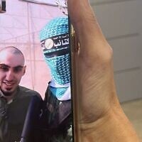 An image of hostage Rom Braslavski and a masked terrorist in a video call while he was still in Hamas captivity on October 13, 2025 (Courtesy)