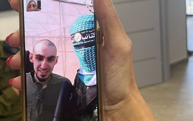 An image of hostage Rom Braslavski and a masked terrorist in a video call while he was still in Hamas captivity on October 13, 2025 (Courtesy)
