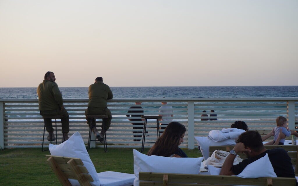 Beachgoers pass time on Zikim Beach in southern Israel, the site of a massacre during Hamas's October 7, 2023, days after reopening to visitors, on October 21, 2025. (Charlie Summers/Times of Israel)