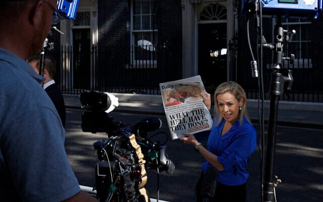A television journalist holds up a copy of  The Daily Mail newspaper, leading with the story of the resignation of Boris Johns as leader of Britain's Conservative Party, as they work outside 10 Downing Street, the official residence of Britain's Prime Minister, in central London on July 8, 2022.  (Photo by CARLOS JASSO / AFP)