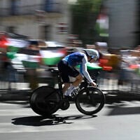 Protesters wave Palestinian flags as Team Israel Premier Tech's British cyclist Jake Stewart competes during the 18th stage of the Vuelta a Espana, a race against the clock between Valladolid and Valladolid in Spain, on September 11, 2025. (Miguel RIOPA / AFP)