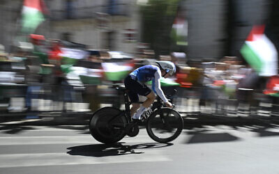 Protesters wave Palestinian flags as Team Israel Premier Tech's British cyclist Jake Stewart competes during the 18th stage of the Vuelta a Espana, a race against the clock between Valladolid and Valladolid in Spain, on September 11, 2025. (Miguel RIOPA / AFP)